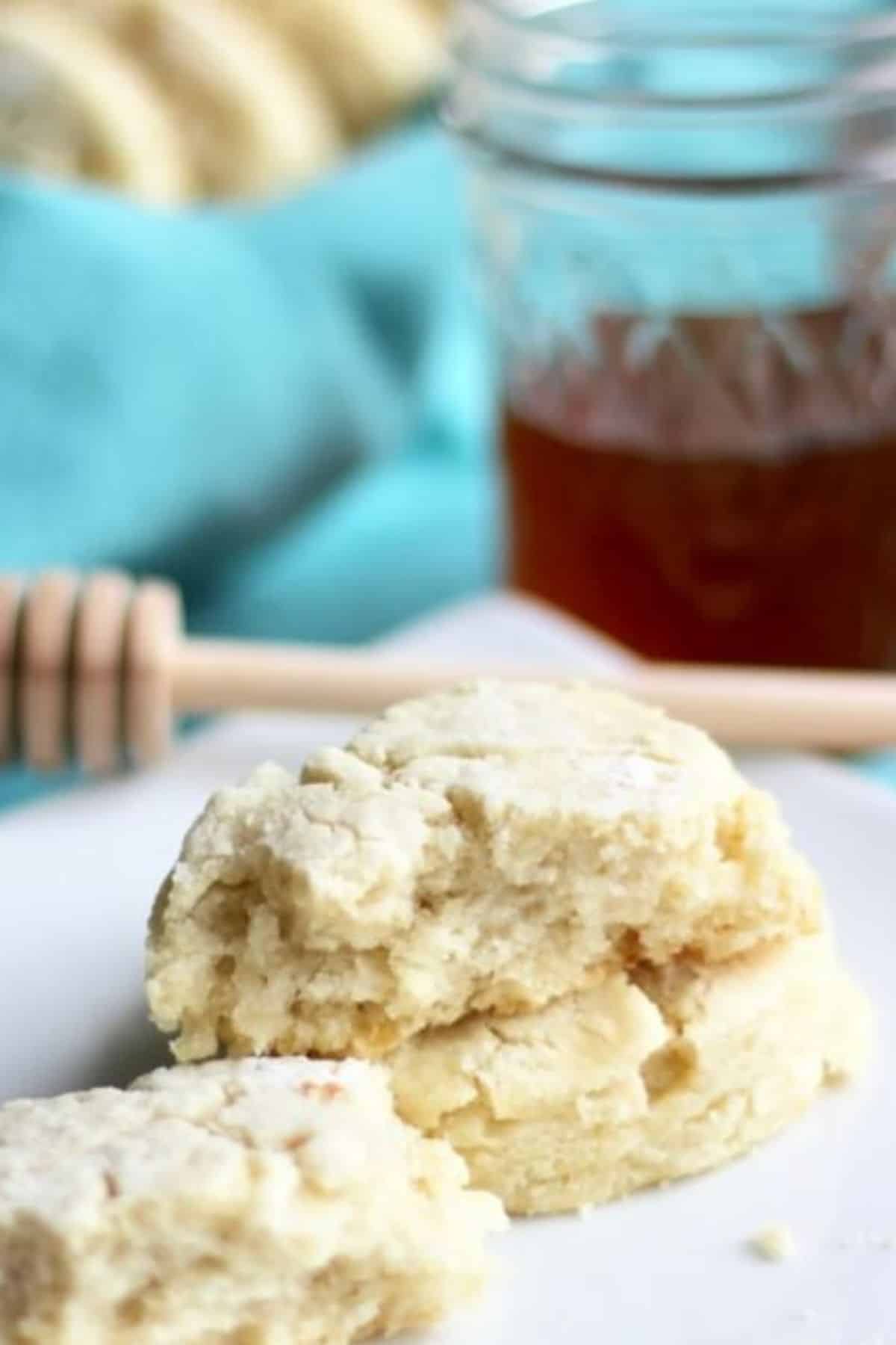 broken open tea biscuits on a white plate with honey in the background.