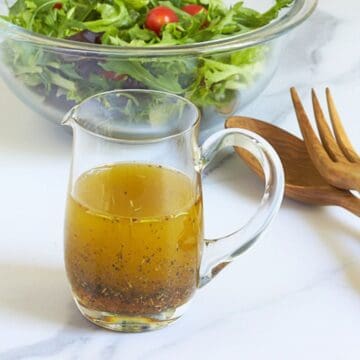 herb vinaigrette in a small, clear glass pitcher.