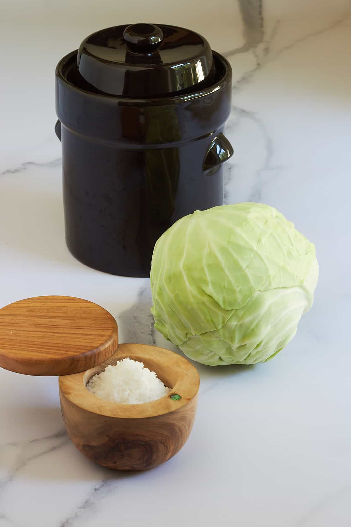 salt, whole cabbage, and fermentation crock.