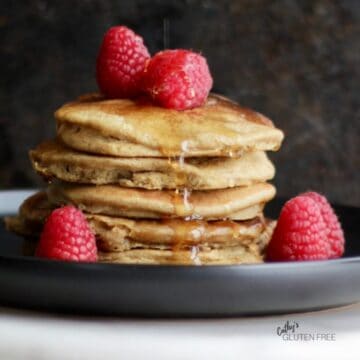 stack of pancakes with raspberries against dark background
