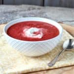 Red borscht topped with cashew yogurt in white bowl