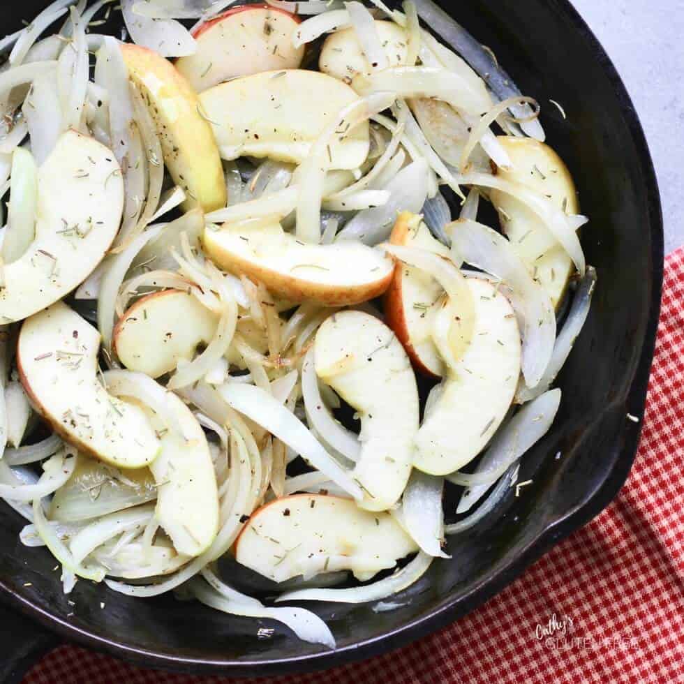 sliced apples and onions in a cast iron skillet