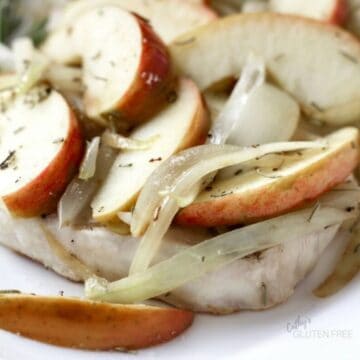 closeup shot of sliced apples and onions on a pork chop