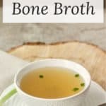clear golden broth in white bowl on white saucer.