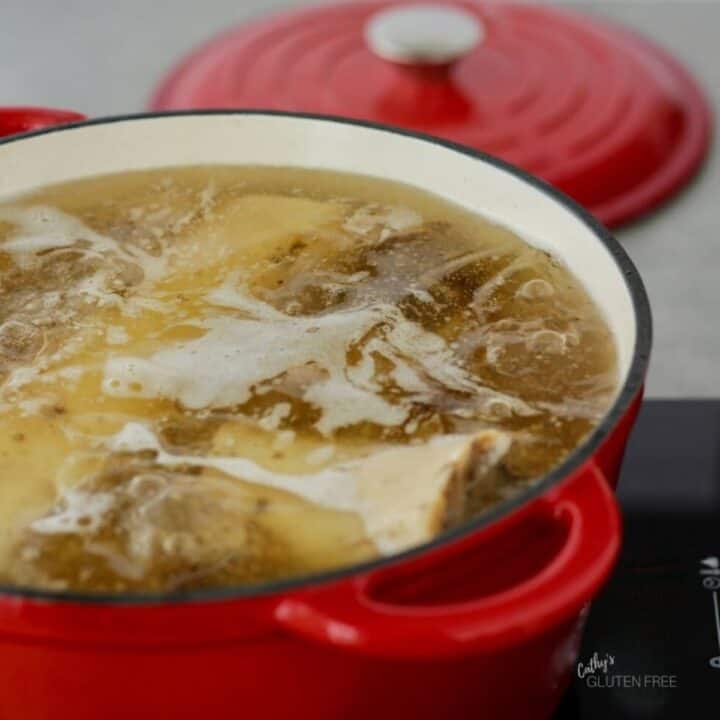 shimmering broth in red pot filled with soup bones