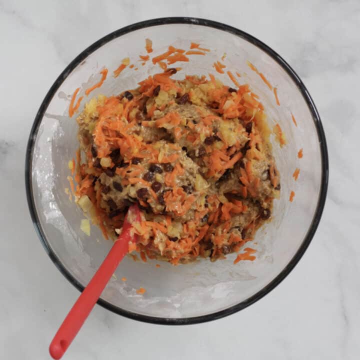 shredded carrot is stirred into batter in glass bowl
