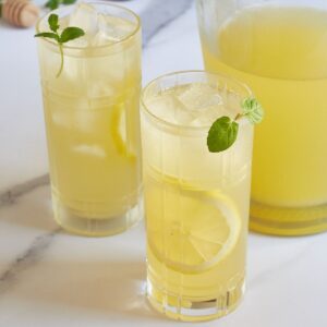 two glasses of lemonade with ice, garnished with mint and lemon