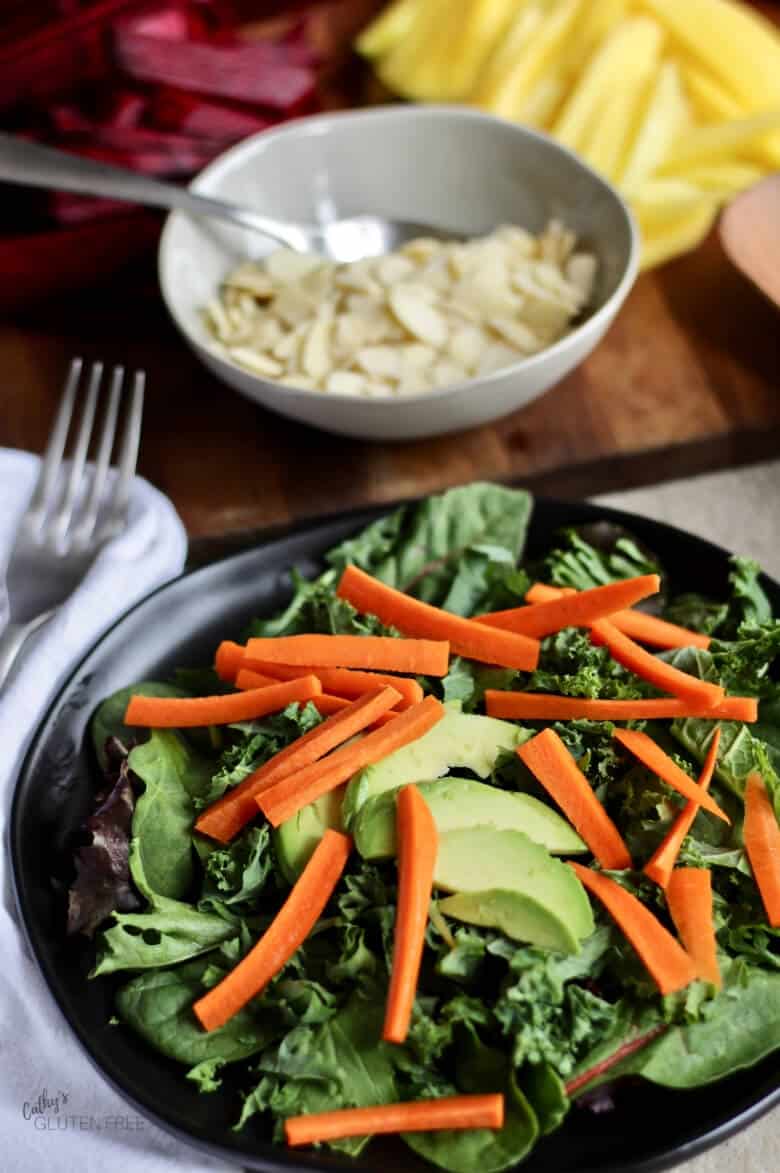 Slivers of carrot layered with avocado over kale and lettuce