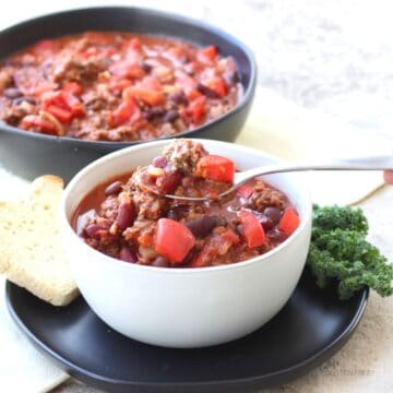 two bowls of chili with ground beef and chunks of red vegetable.