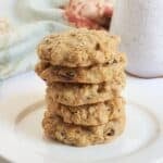 oatmeal cookies with raisins stacked on a white plate.