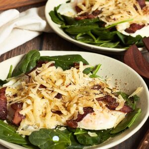 shredded cheese over chopped bacon, fried egg, and spinach.
