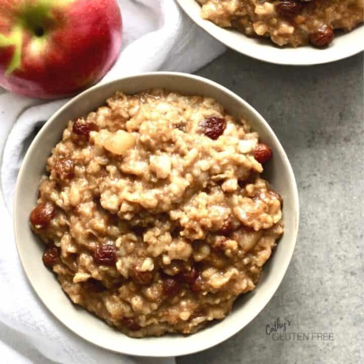 looking down into a white bowl of porridge with an apple to the side.