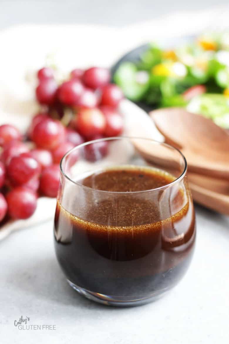 balsamic vinaigrette in glass, grapes, and lettuce salad in background