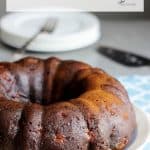 dark brown tubulars-shaped cake with white plates stacked in background