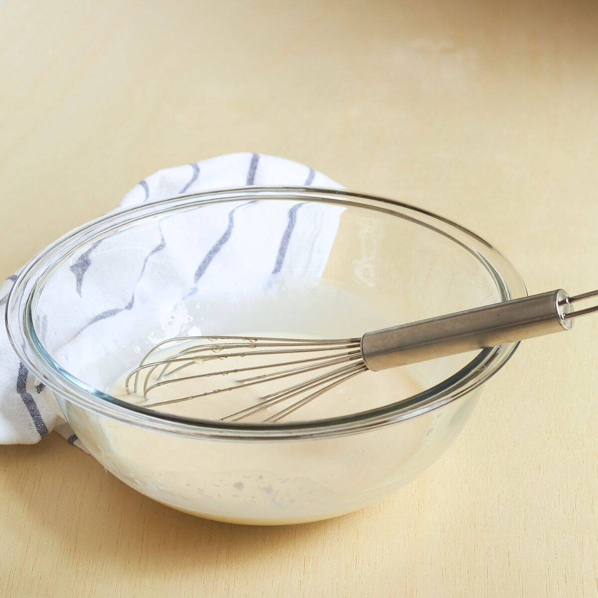 creamy coleslaw dressing with whisk in large glass bowl.