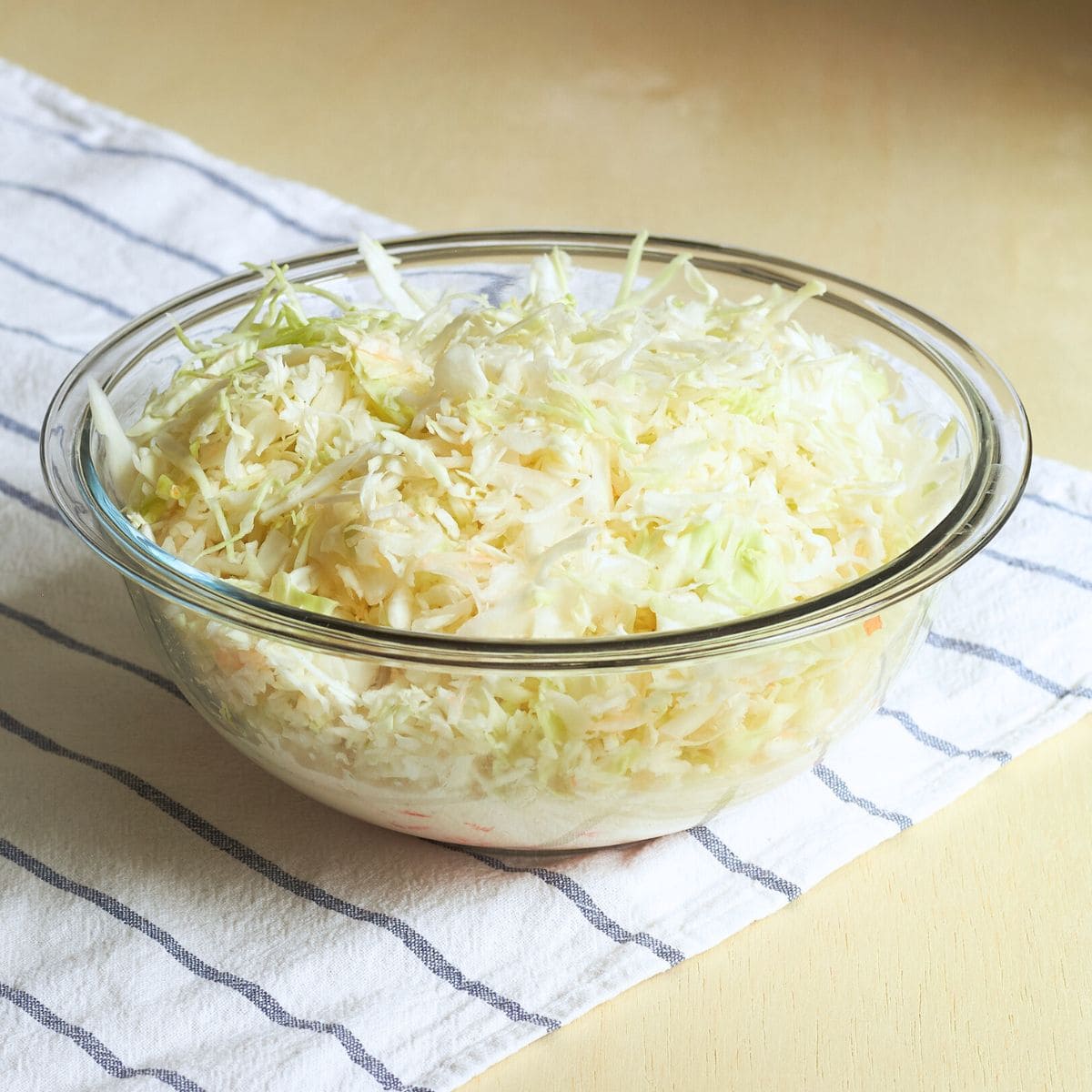 shredded cabbage, carrot, and onion, in large glass bowl.