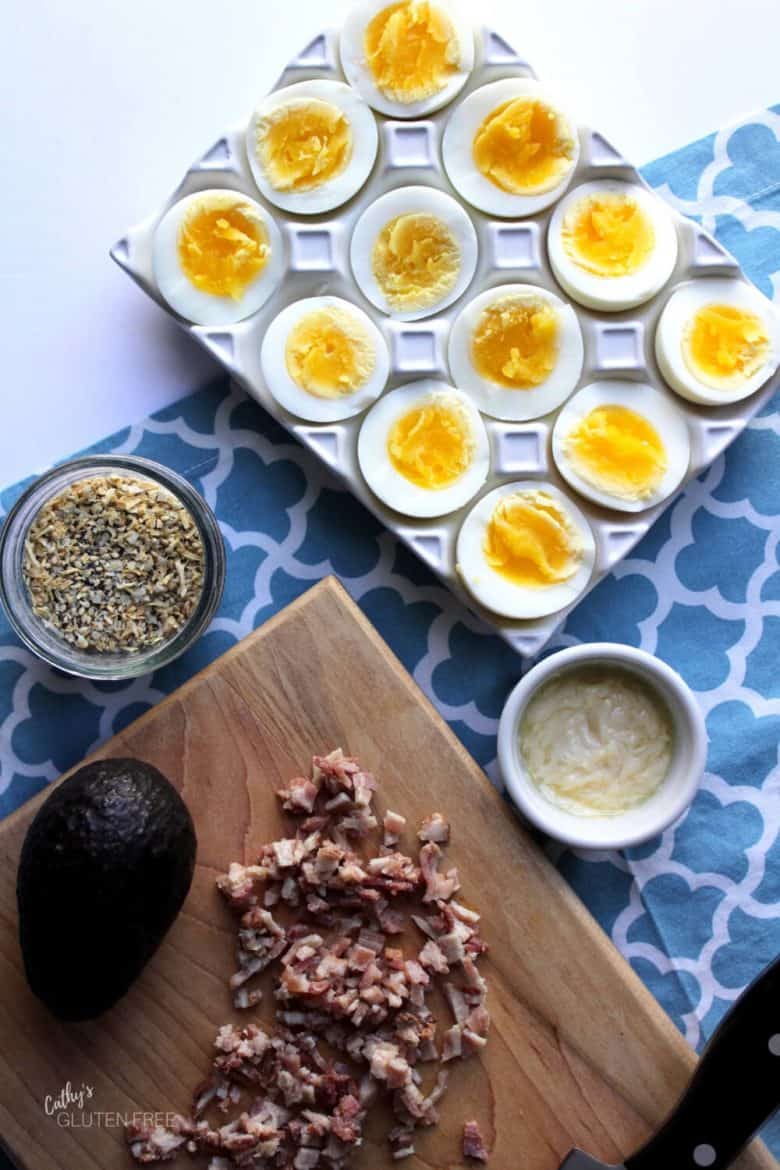 boiled eggs split open, Everything Seasoning, mayonnaise, chopped bacon, and avocado