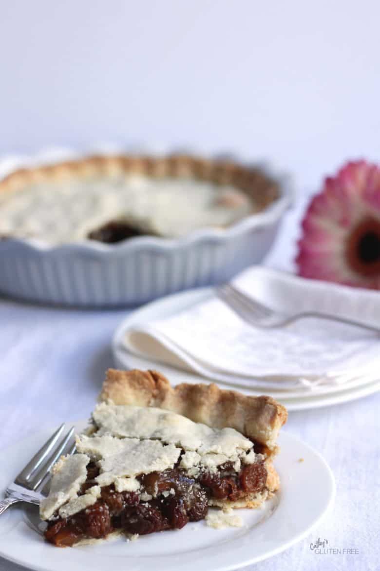 baked pie sliced and plated with white cloth napkins, pie, and pink flower in background