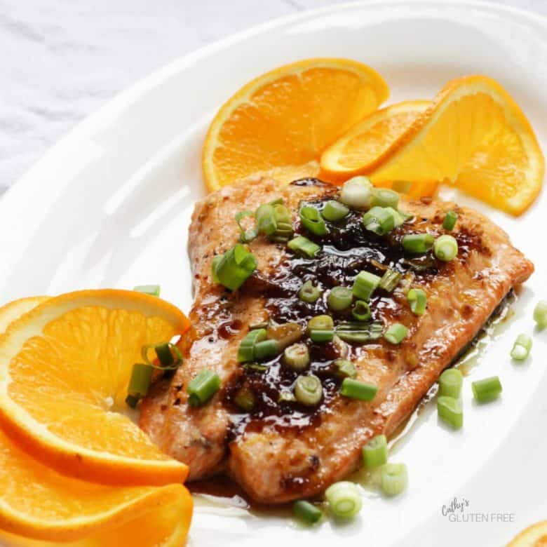 Chopped green onion tops a fillet of cooked salmon. 