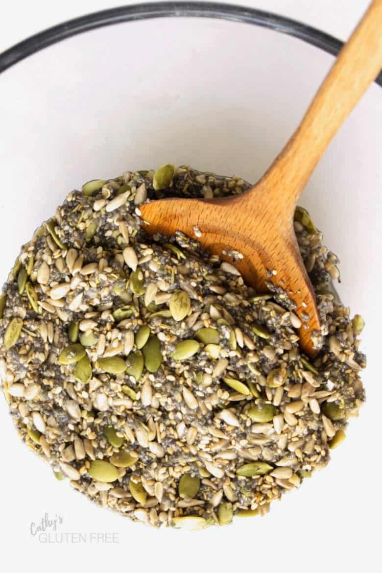 overhead view of seed mixture in clear glass bowl with wooden spoon