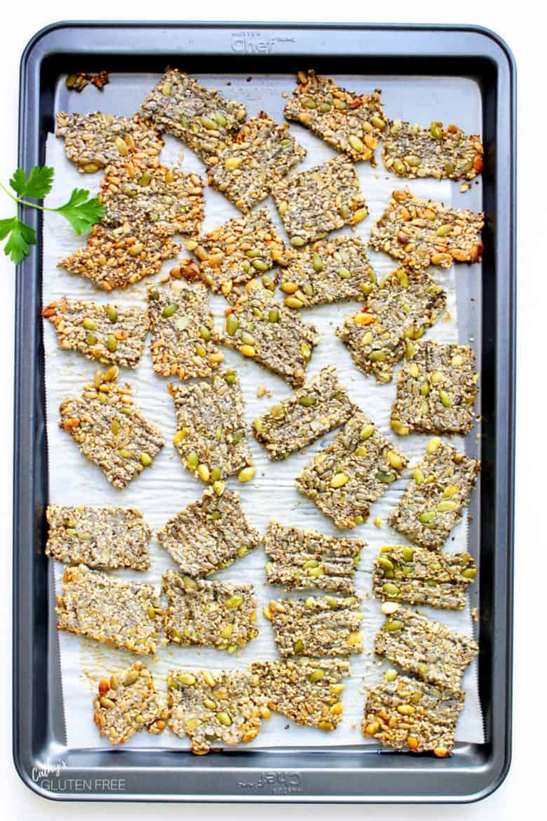 Keto 4-seed crackers spread randomly on a parchment-lined baking sheet