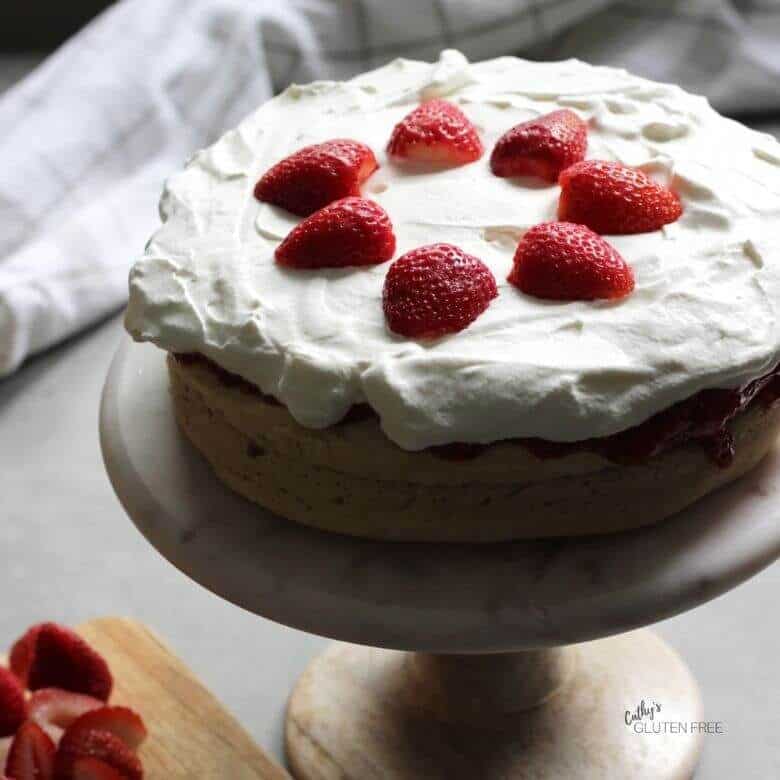 two layers of light cake with whipped cream and strawberries on top