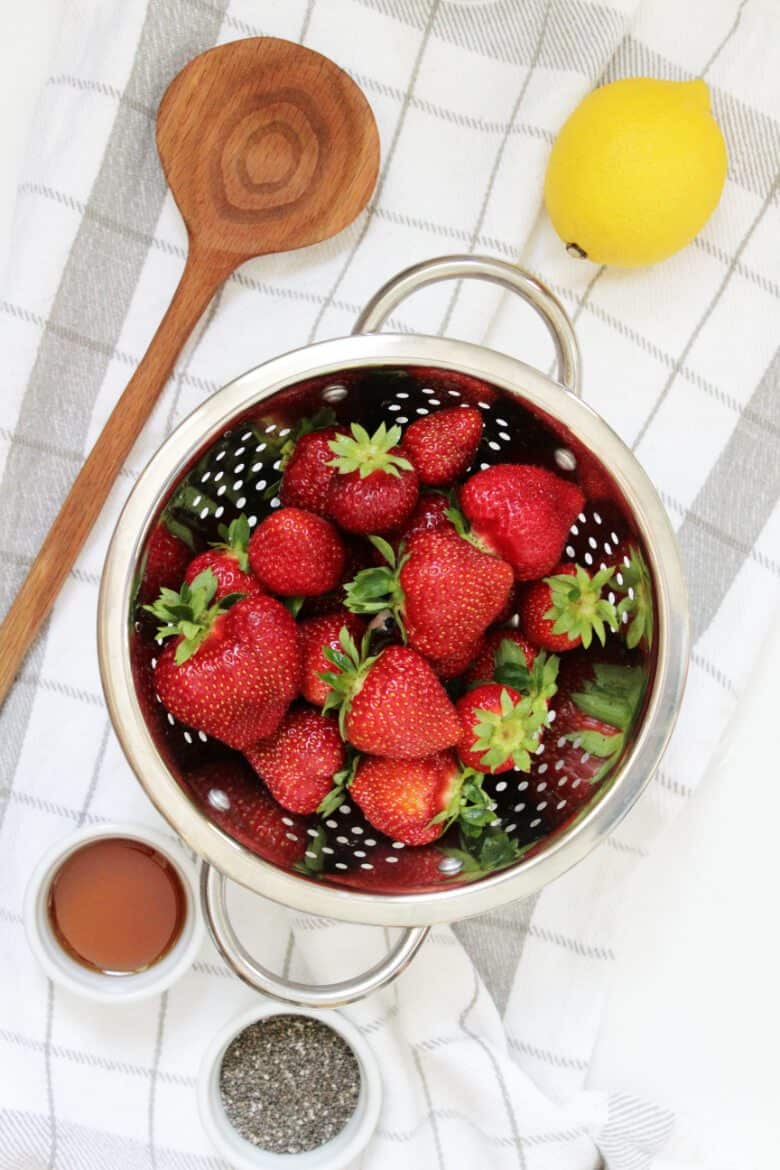 strawberries in a colander with lemon and chia seeds on the side