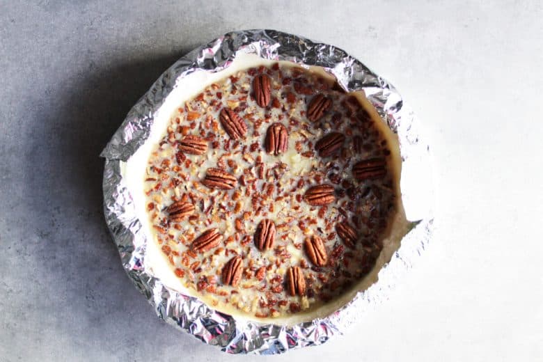 aluminum foil collar wrapped around the edge of an unbaked pecan pie