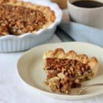 a slice of pecan pie with a bite lifted out by a fork.