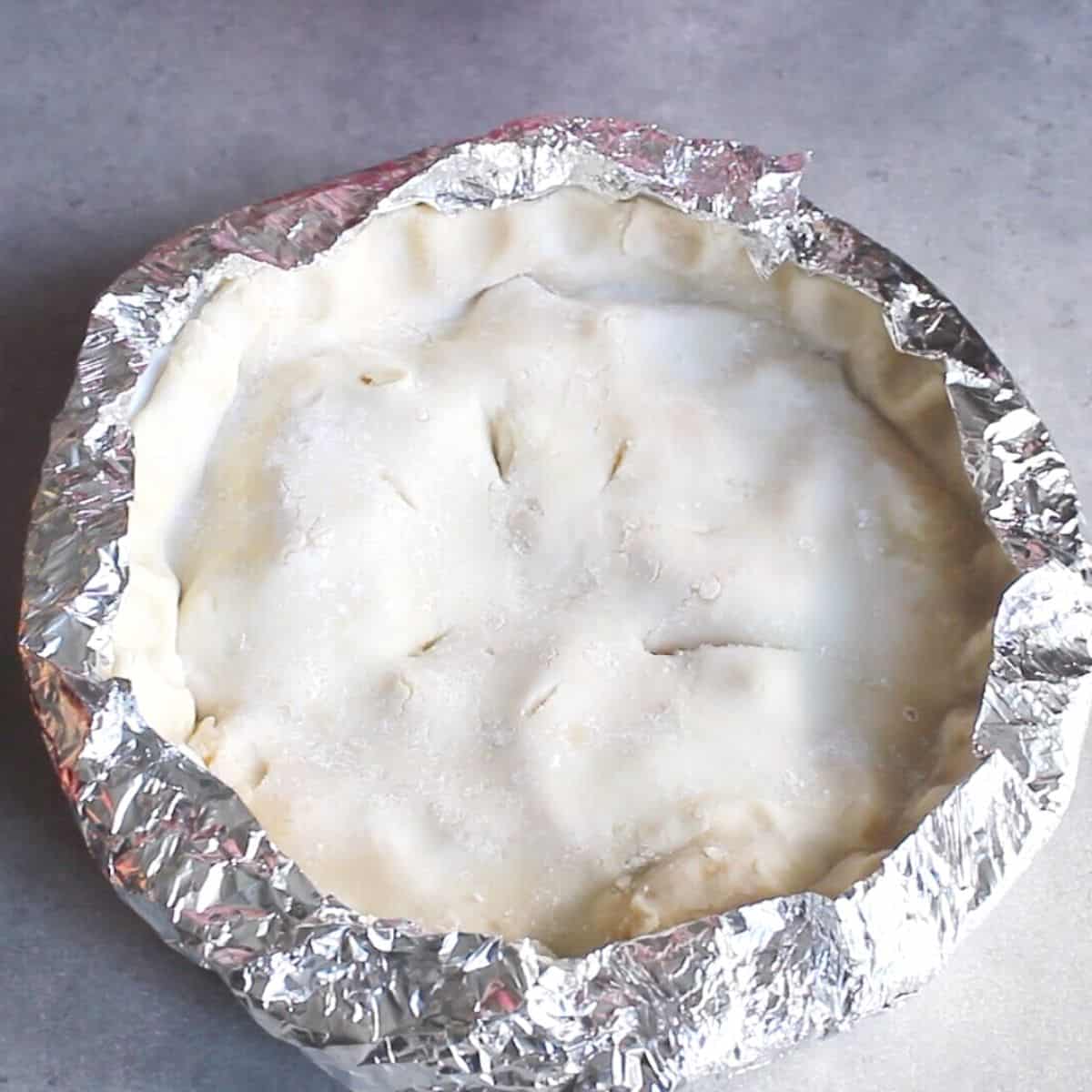 unbaked pie with foil collar crimped around the edges.