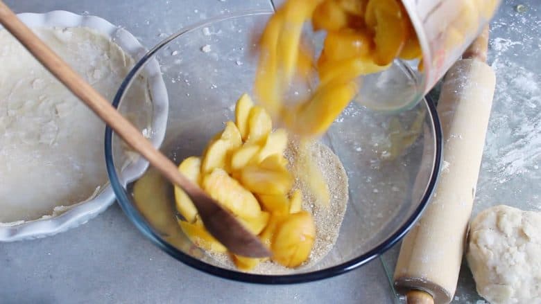 sliced peaches are poured into glass bowl