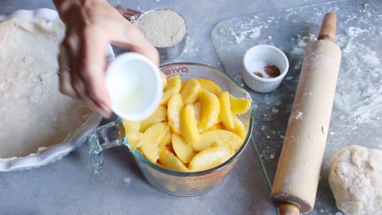 lemon juice is poured onto fresh peach slices