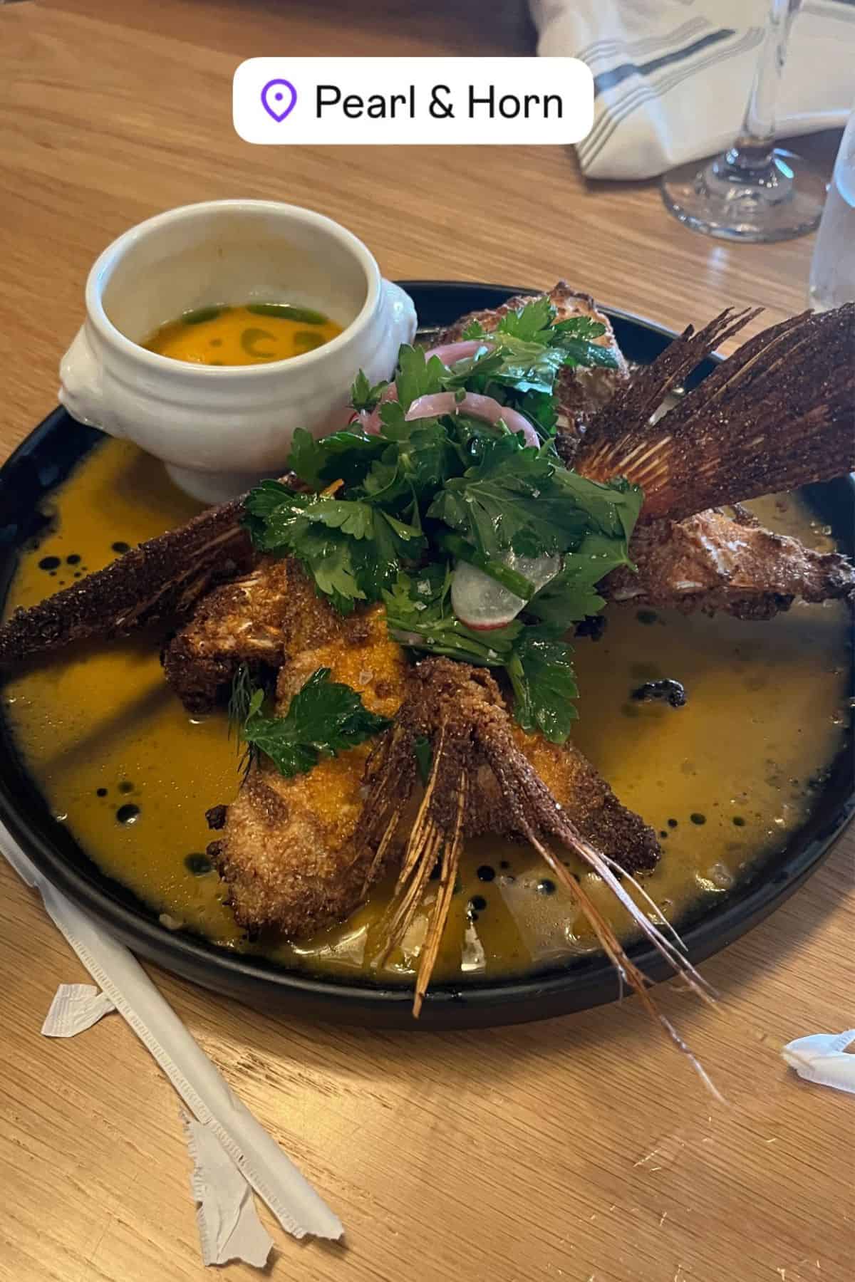 fried red snapper elegantly served on a black plate.