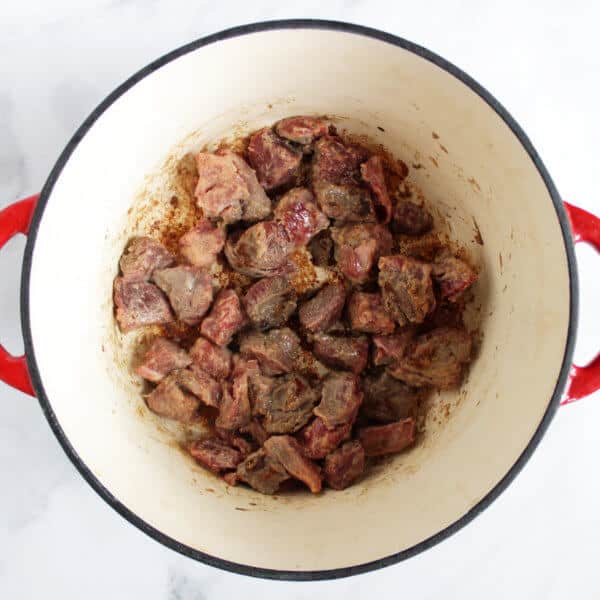 beef cubes cooking in bottom of enamelled pot