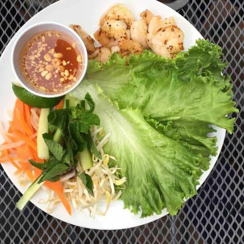 lettuce, shrimp, sprouts, carrot slivers, and sauce on white plate of Khon, one of the restaurants in Pensacola Florida