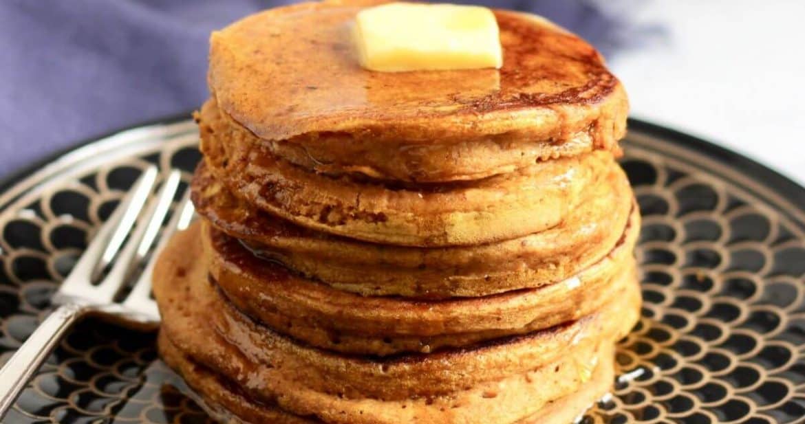stack of pancakes with pat of butter on top and maple syrup drizzled all over