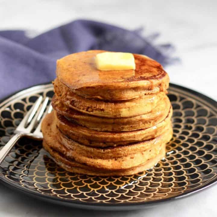 stack of pancakes with pat of butter on top and maple syrup drizzled all over