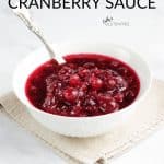 Simple cranberry sauce in white bowl on linen napkin with silver spoon