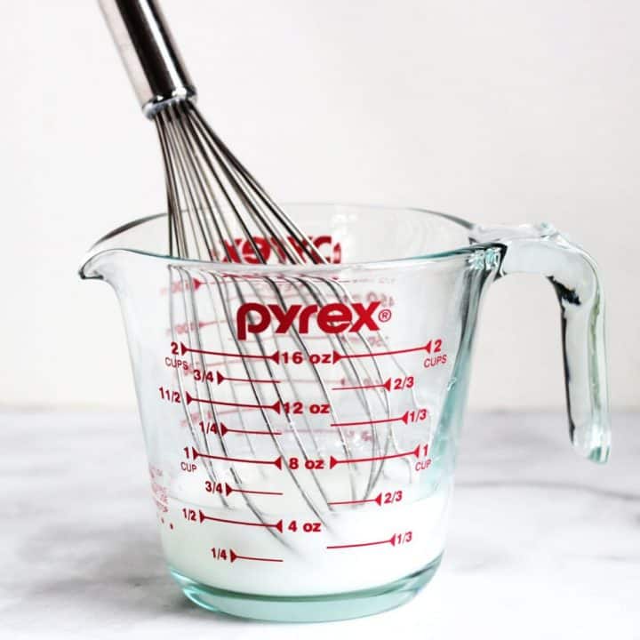 whisk in white liquid in pyrex measuring cup