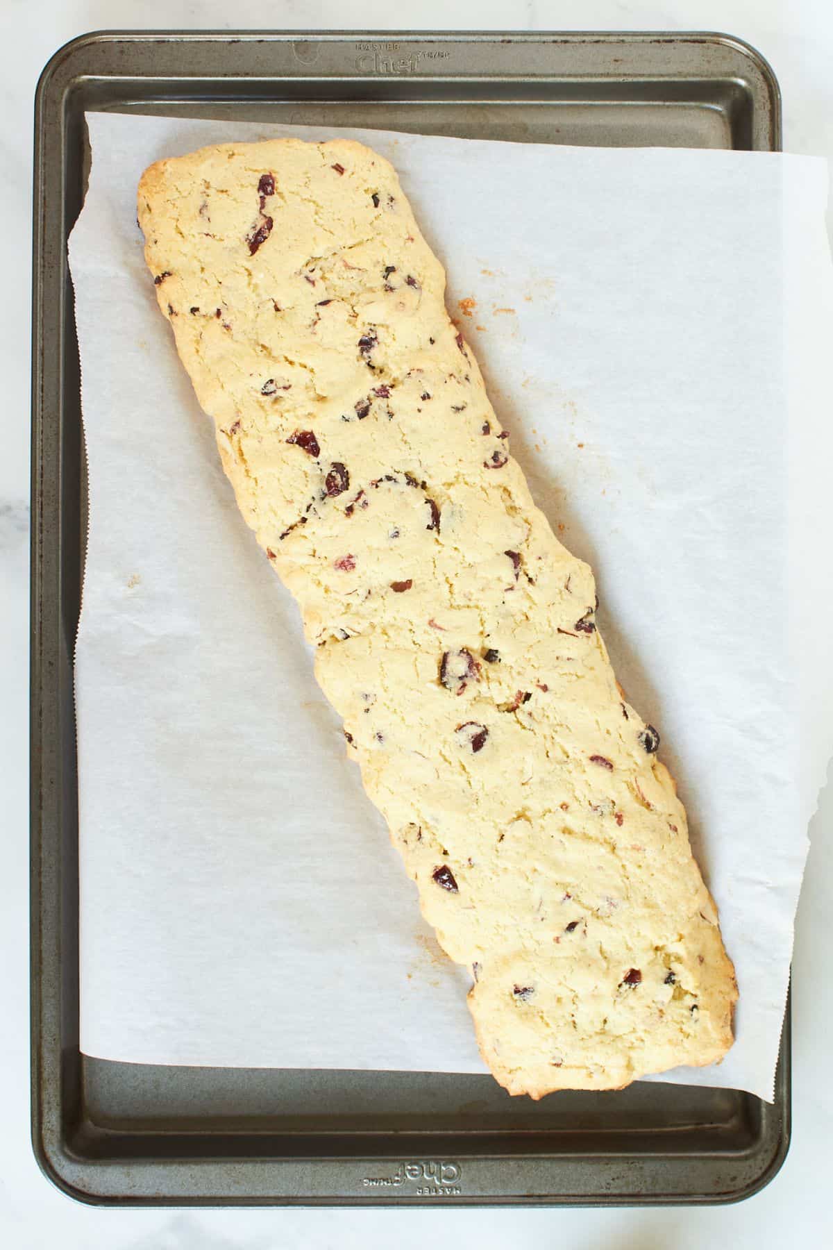baked-gluten-free cranberry biscotti log on tray.