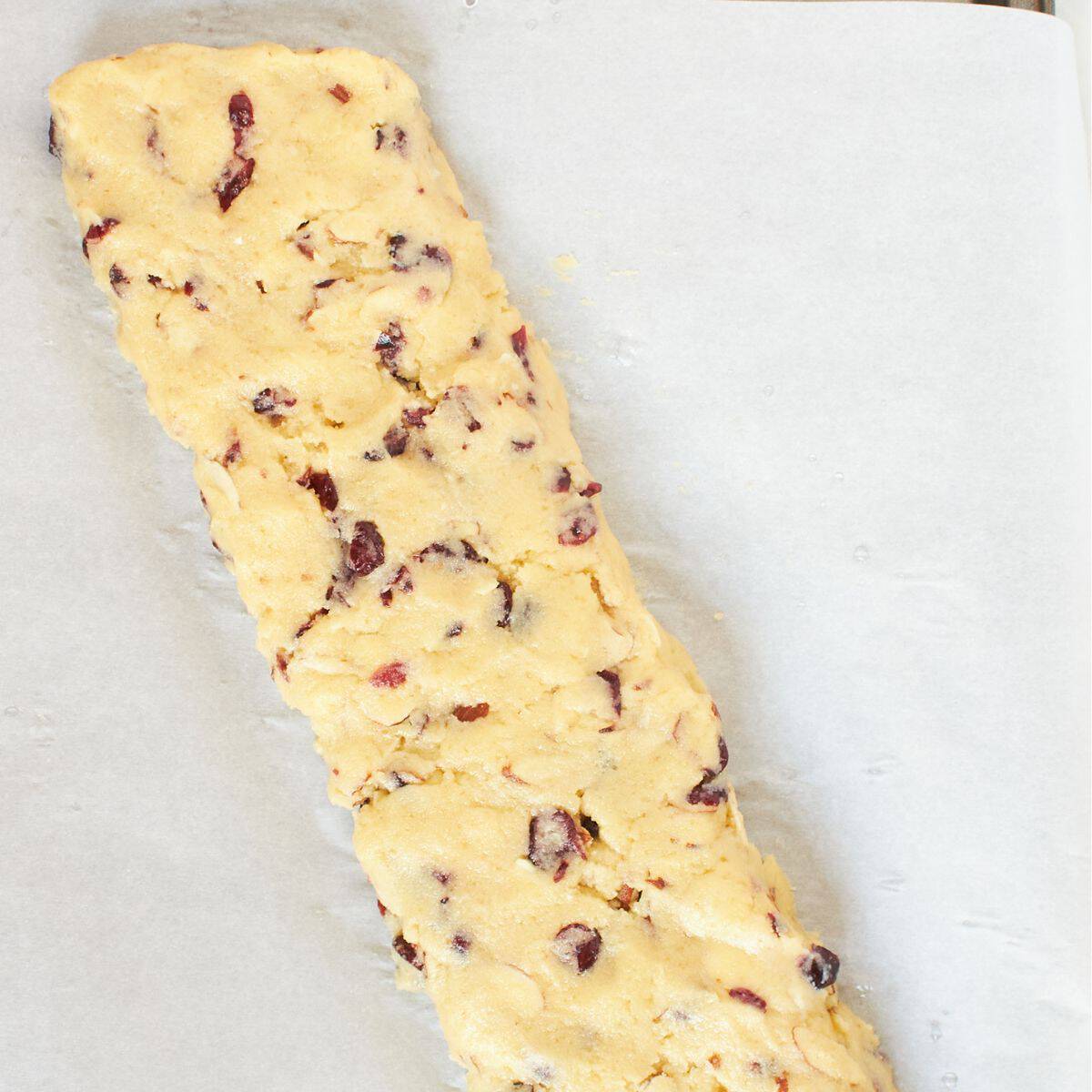cranberry biscotti dough spread into a flatish log on parchment paper.