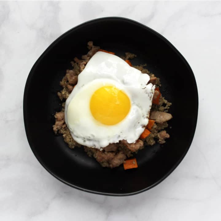 top down view of fried egg, avocado slices, and salsa on quinoa, sweet potatoes, and sausage