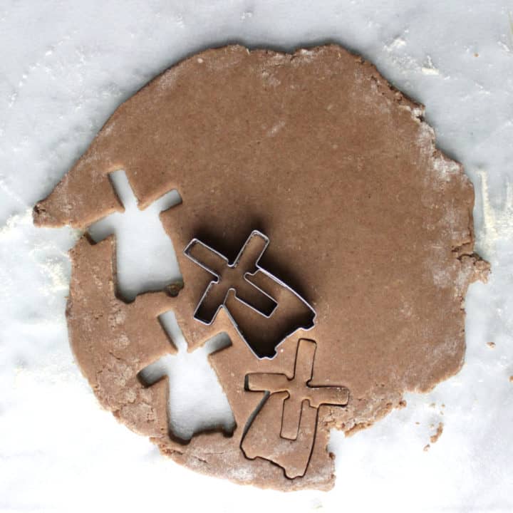 top down view of cookie cutter cutting out a few windmill-shaped cookies