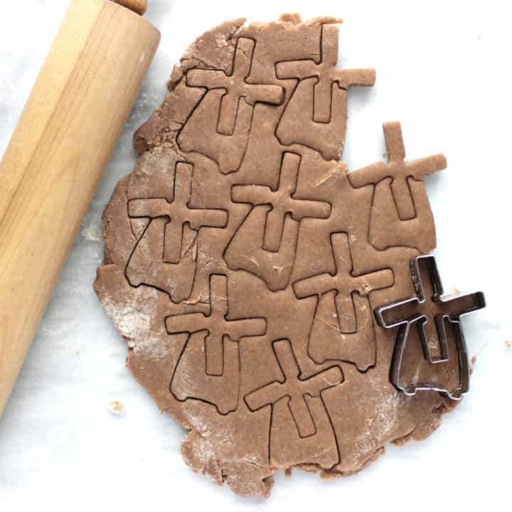 top down view of windmill-shaped cookies cut into rolled dough with rolling pin to side