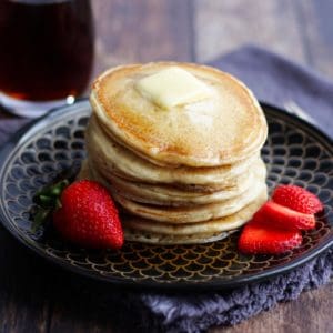 stack of gluten free pancakes with butter on top, garnished with strawberries