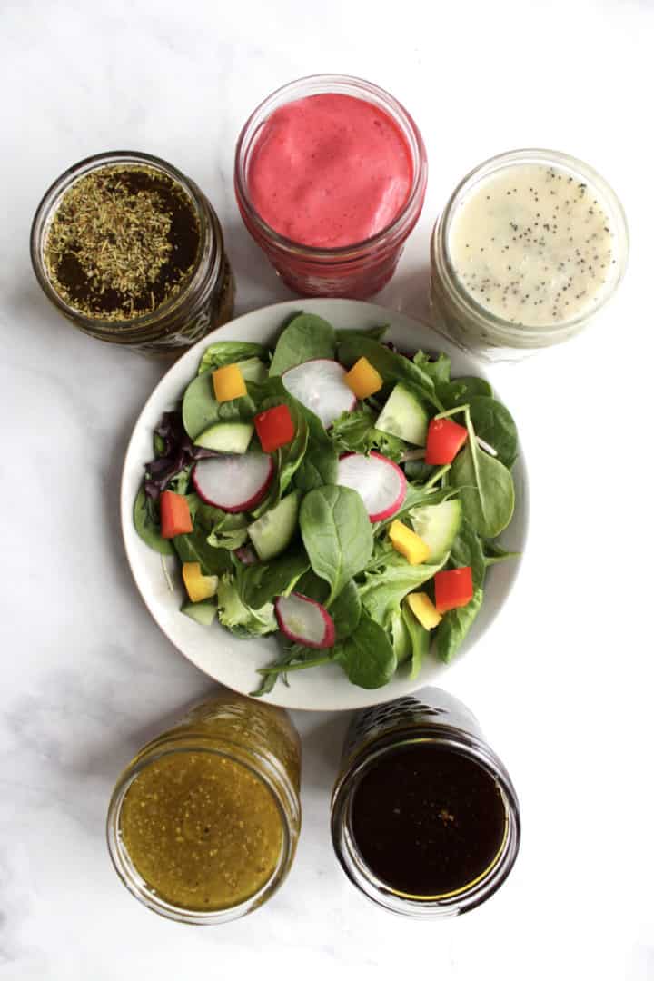 top down view of salad dressings surrounding a bowl of salad