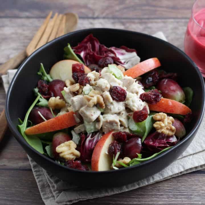 chicken waldorf salad in black bowl on linen napkin