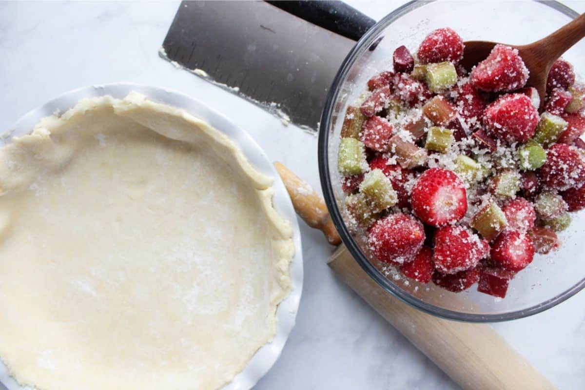 unbaked gluten free pie crust with strawberry rhubarb filling in glass bowl to the side