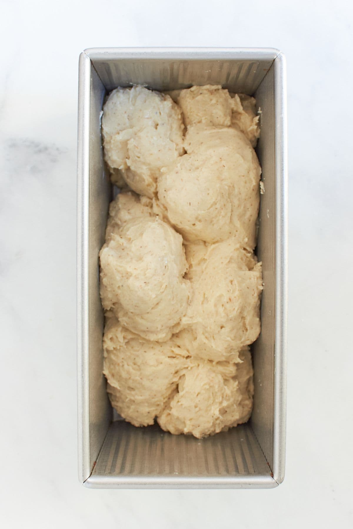 balls of gluten-free dough in bread loaf pan.