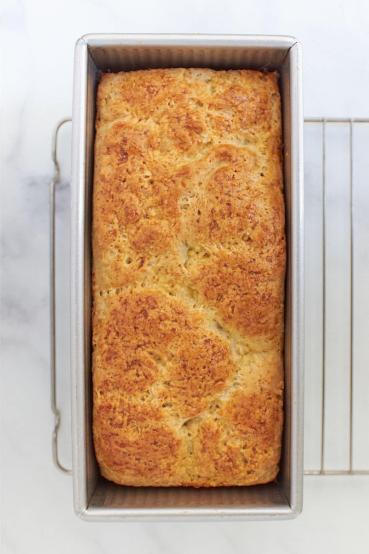 baked golden loaf of gluten-free brioche bread in pan, as seen from above.